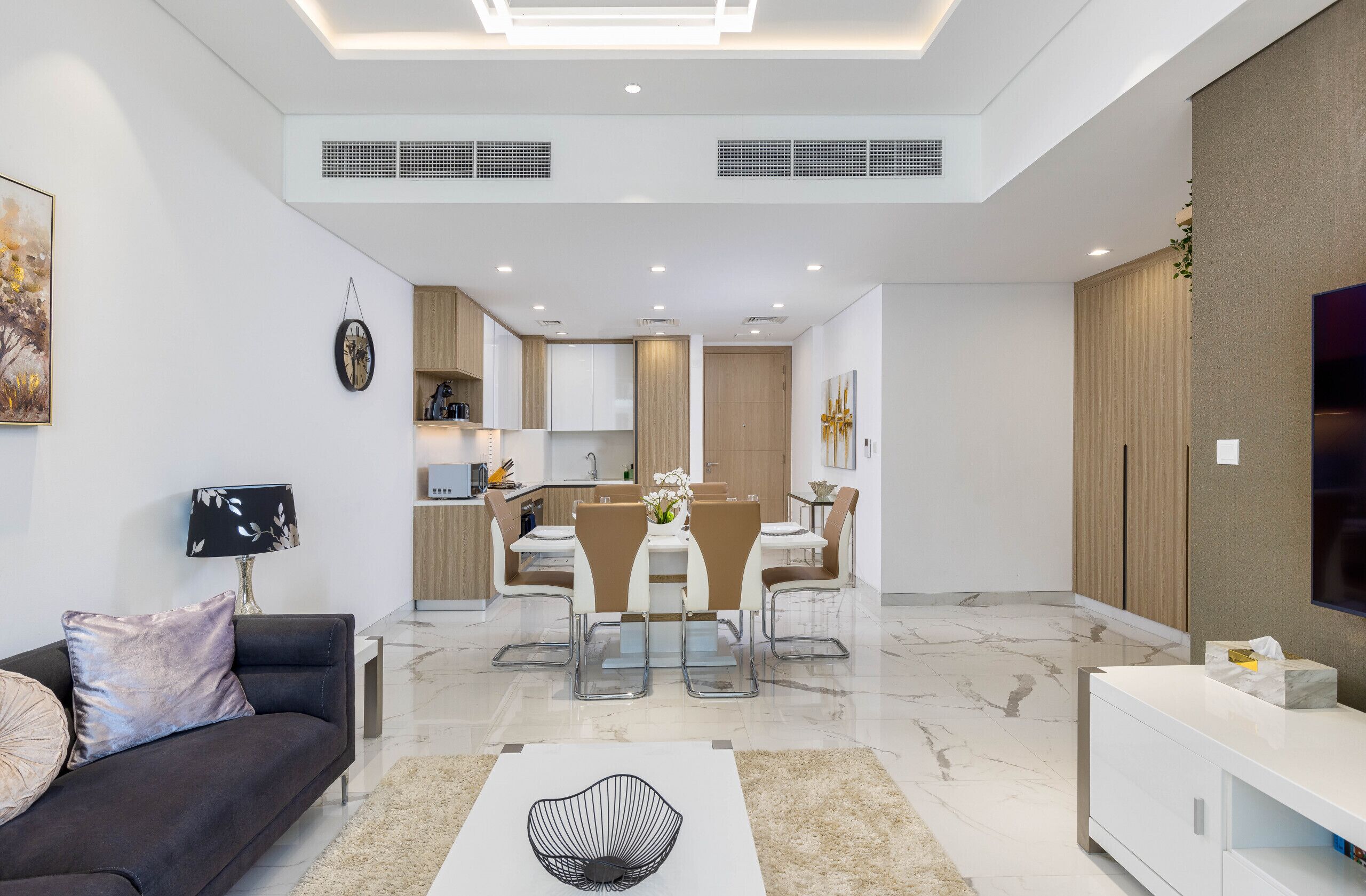 A modern living room with a sofa, a coffee table, and a dining area with a table and chairs.