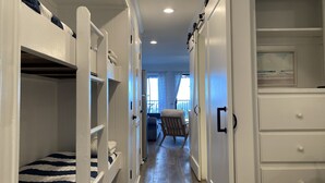 Un couloir étroit, avec des lits superposés d’un côté et une commode de l’autre.
