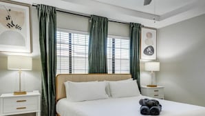 Ein ordentlich eingerichtetes Schlafzimmer mit einem Bett, zwei Nachttischen und einem Fenster mit Vorhängen.