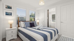 A bedroom with a bed, nightstands, a lamp, and a door. - By the Bay on Duncan by Experience Jervis Bay (Vincentia)