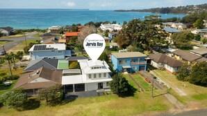 An aerial view of a residential area with houses, a road, and a body of water in the background. - By the Bay on Duncan by Experience Jervis Bay (Vincentia)