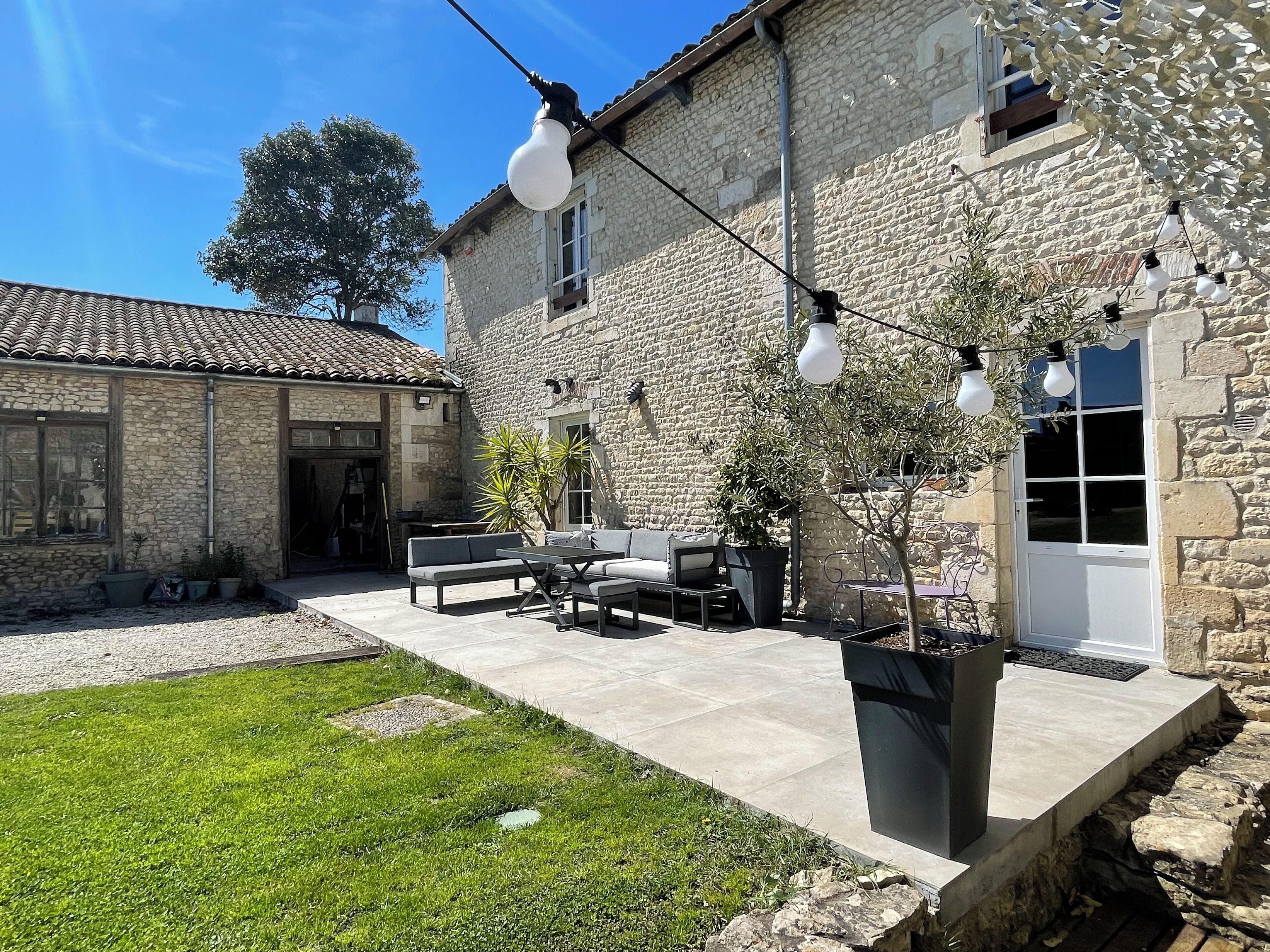 Un edificio de piedra con un patio que incluye mobiliario exterior y plantas en macetas.