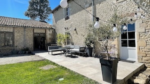 Un edificio de piedra con un patio que incluye mobiliario exterior y plantas en macetas.