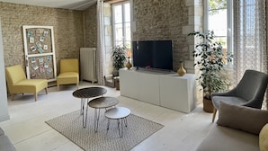 Una sala de estar con pared de piedra, un ventanal grande, un televisor de pantalla plana y una planta en maceta.