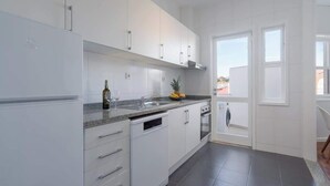 A modern kitchen with white cabinets, a granite countertop, and a built-in dishwasher. - Stylish Comfortable Flat w/ Balcony by HostWise (Porto)