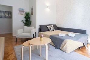 Una habitación moderna con sofá, una mesita, una planta en maceta y un cartel en la pared.