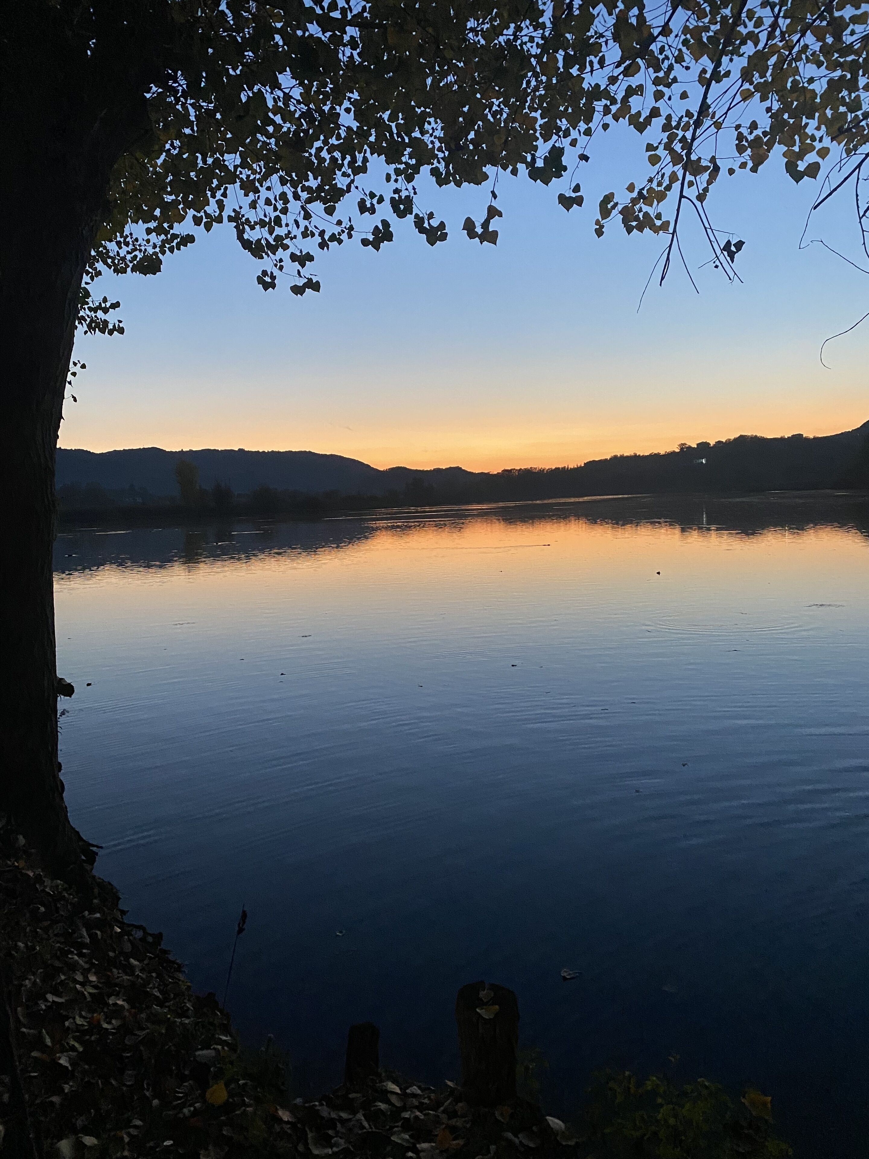 A calm lake with a clear sky, surrounded by hills.