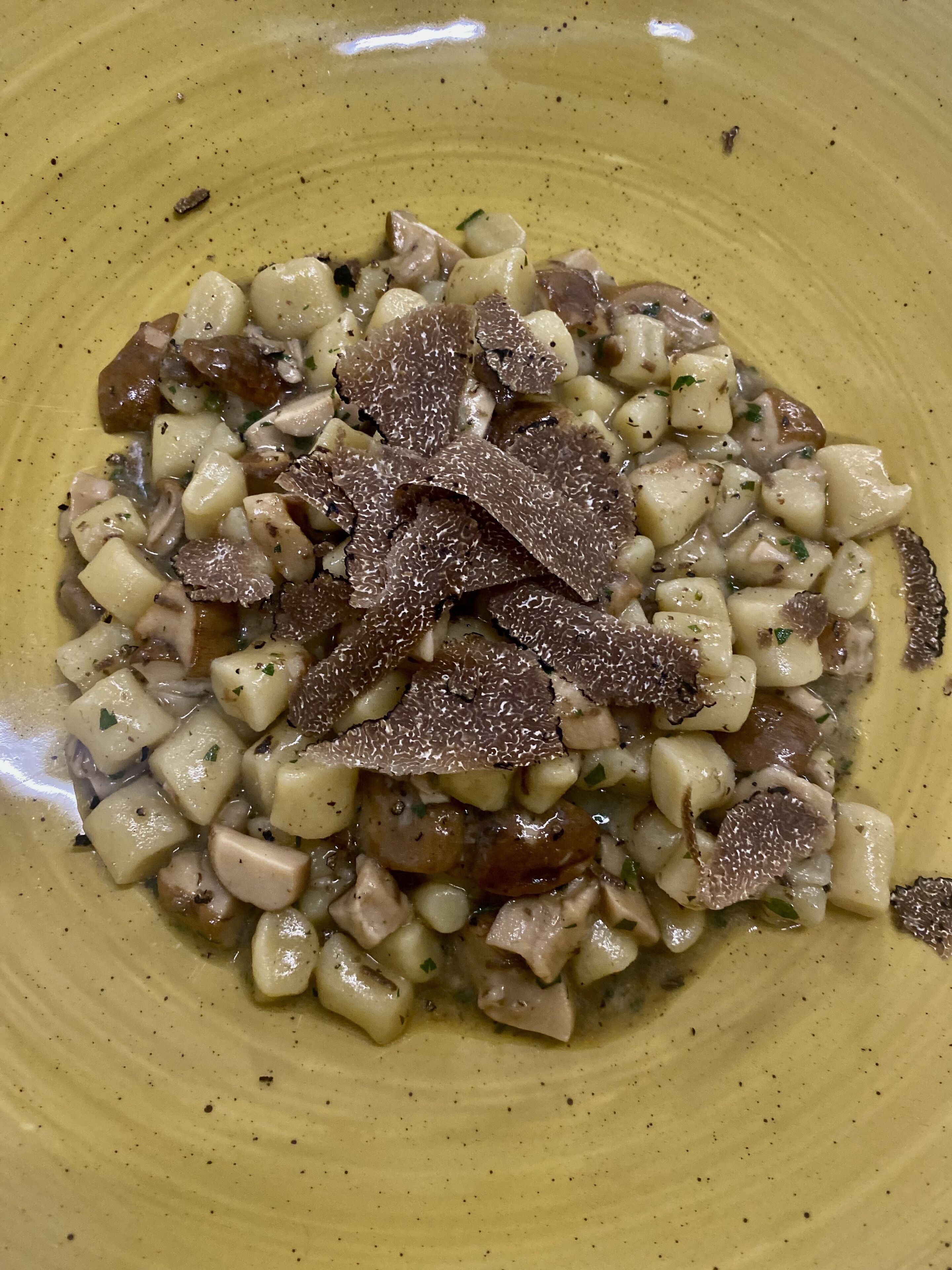 A plate of food with diced potatoes, mushrooms, and truffles.