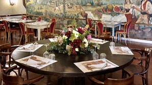 A restaurant with round tables, red chairs, and a mural on the wall depicting a pastoral scene. - Albergo Mingone (Arpino)