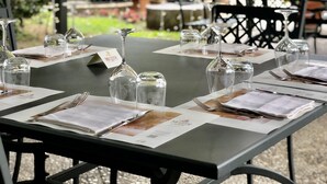 An outdoor dining area with tables set for two, each with a menu, cutlery, and glassware. - Albergo Mingone (Arpino)