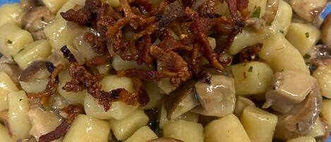 A close-up of a dish with cubed potatoes, mushrooms, and crispy bacon on a blue plate.