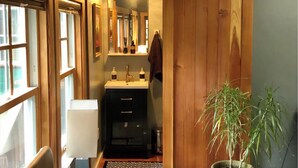 A narrow hallway with a wooden door, a sink with two bottles, and a mirror. - Hillside Retreat in the Redwoods w/ Hot Tub (Guerneville)