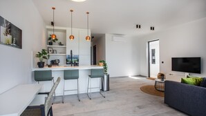 A modern living space with a kitchen, dining area, and a seating area with a sofa and TV. - Blue Bay - The Reef (Sint Michiel)