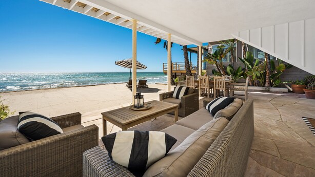 A beachside patio with wicker furniture, a table with a lantern, and a view of the ocean. - 35581 Beach Road: 4  BR, 4  BA House in Dana Point, Sleeps 8 (Dana Point)