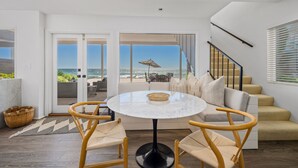 A modern living room with a round table, two wooden chairs, a sofa, and a view of the ocean through large sliding doors. - 35581 Beach Road: 4  BR, 4  BA House in Dana Point, Sleeps 8 (Dana Point)