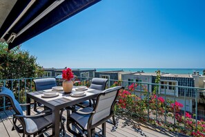 Terraço com mesa posta para refeições, com vista para a costa.