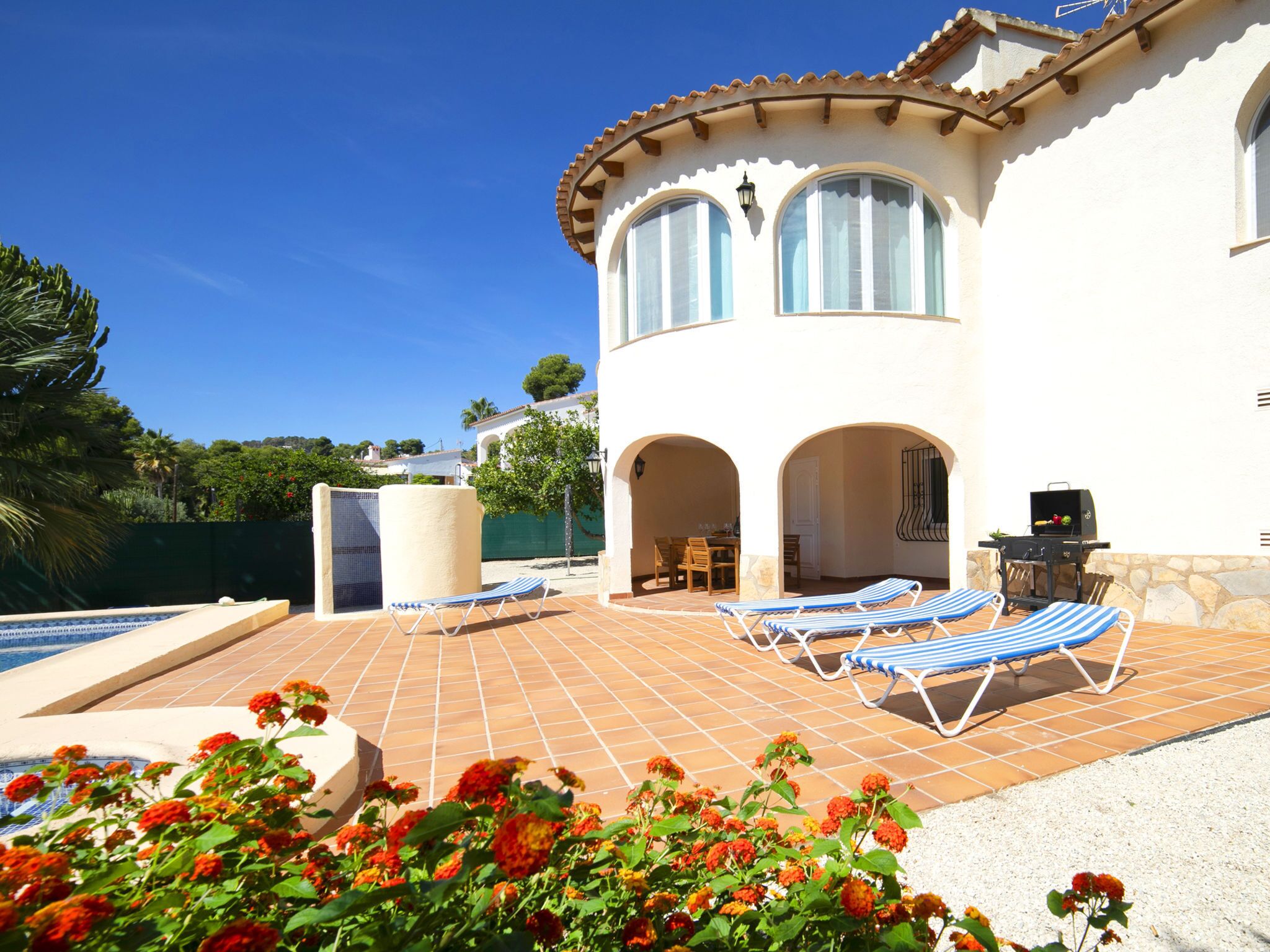 A villa with a swimming pool, outdoor seating, and a barbecue area.