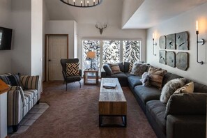 Uma sala de estar com sofá, poltrona, mesa de centro e lareira.