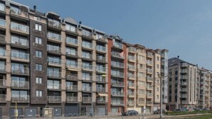 A multi-story residential building with balconies, a central vertical structure, and a parking area in front. - Skyview with parking and balcony by Interhome (Blankenberge)