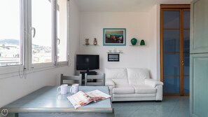 A living room with a white sofa, a TV, and a table with two mugs and a magazine. - Italianway - Roma 70 (Sanremo)