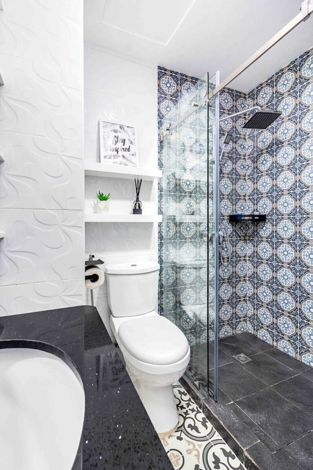 Une salle de bain avec des toilettes blanches, une douche en verre et un lavabo en marbre noir.