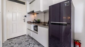 A modern kitchen with white cabinets, a stainless steel refrigerator, and a patterned floor.