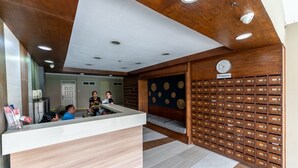 A reception area with a wooden reception desk, a wall of numbered mailboxes, and a clock.