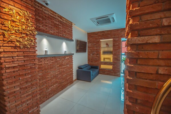 A modern interior with brick walls, a sofa, and a shelf with bottles.