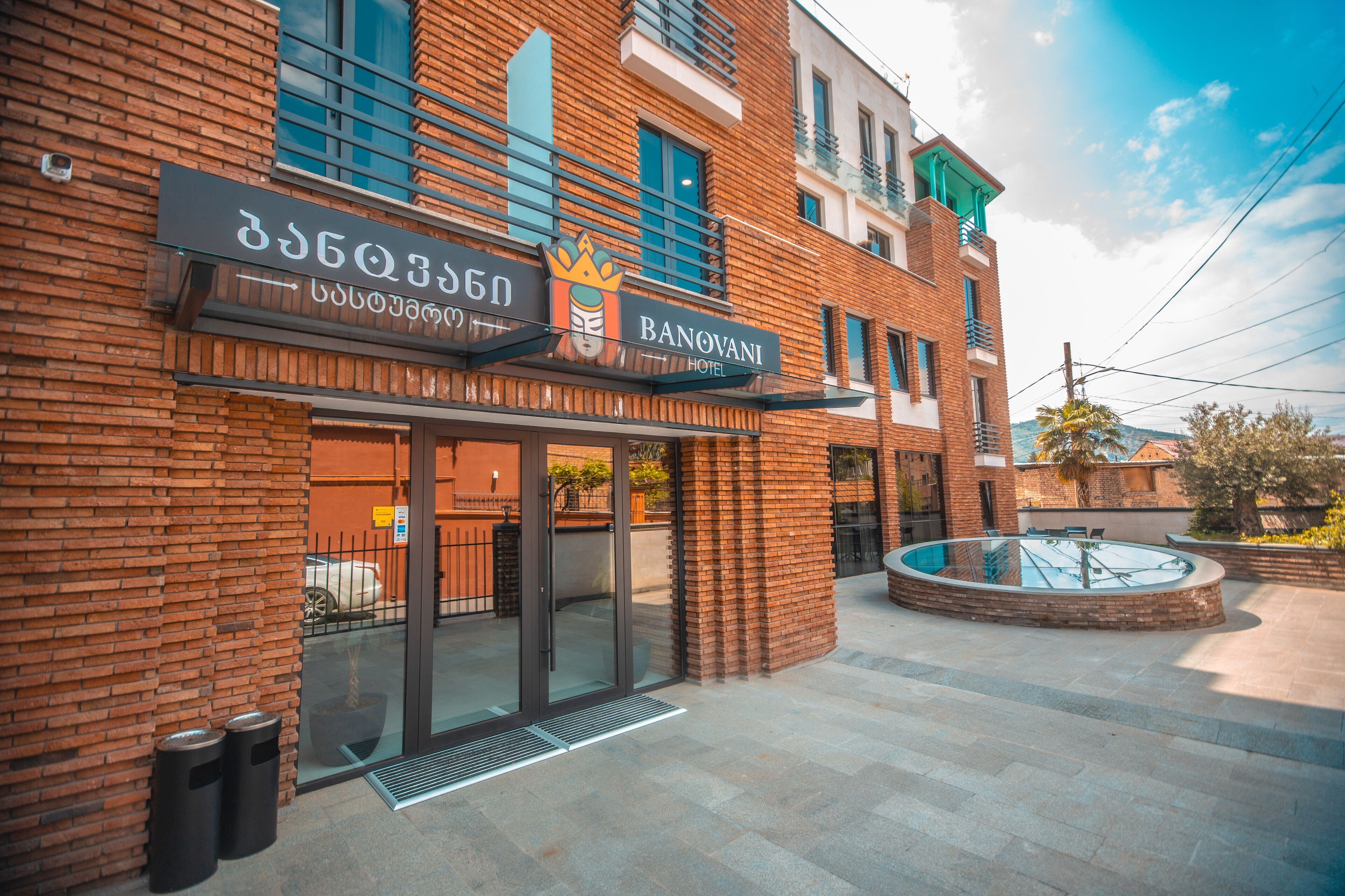 A hotel entrance with a modern brick facade, a glass door entrance, and a circular outdoor seating area.