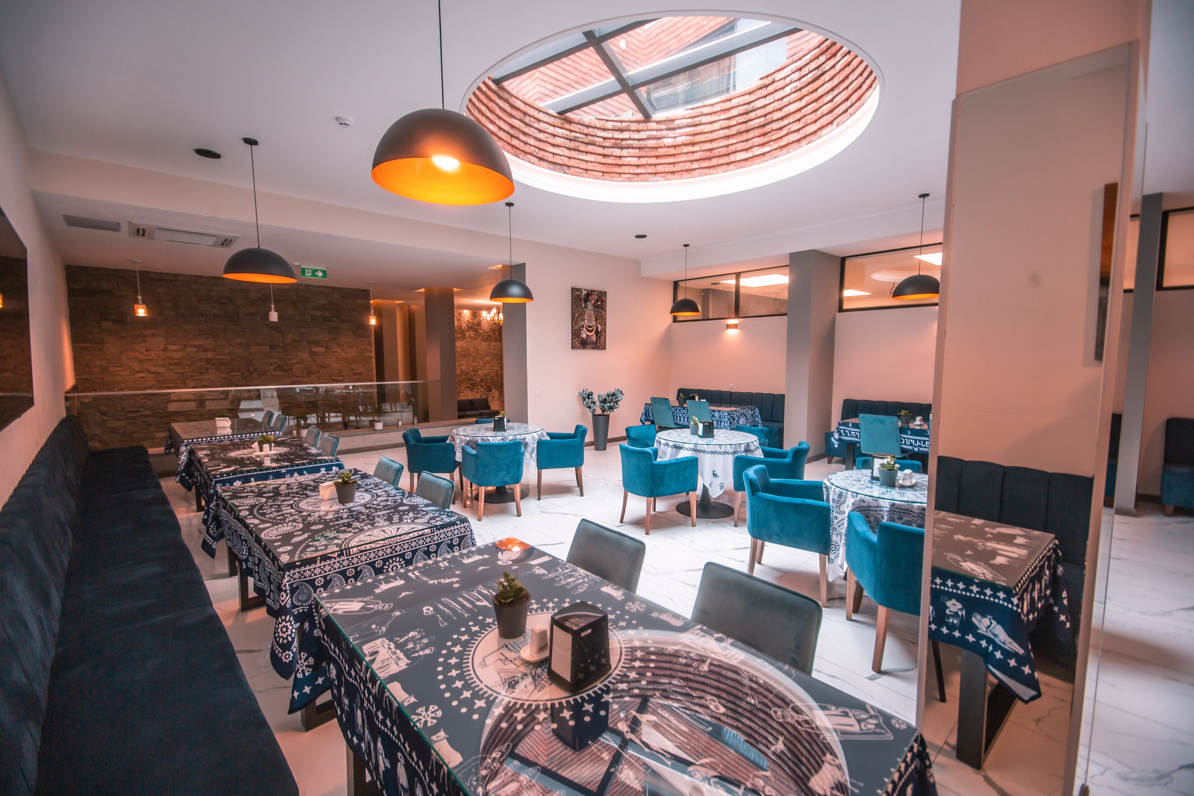 A modern dining area with round tables, blue chairs, and pendant lighting.