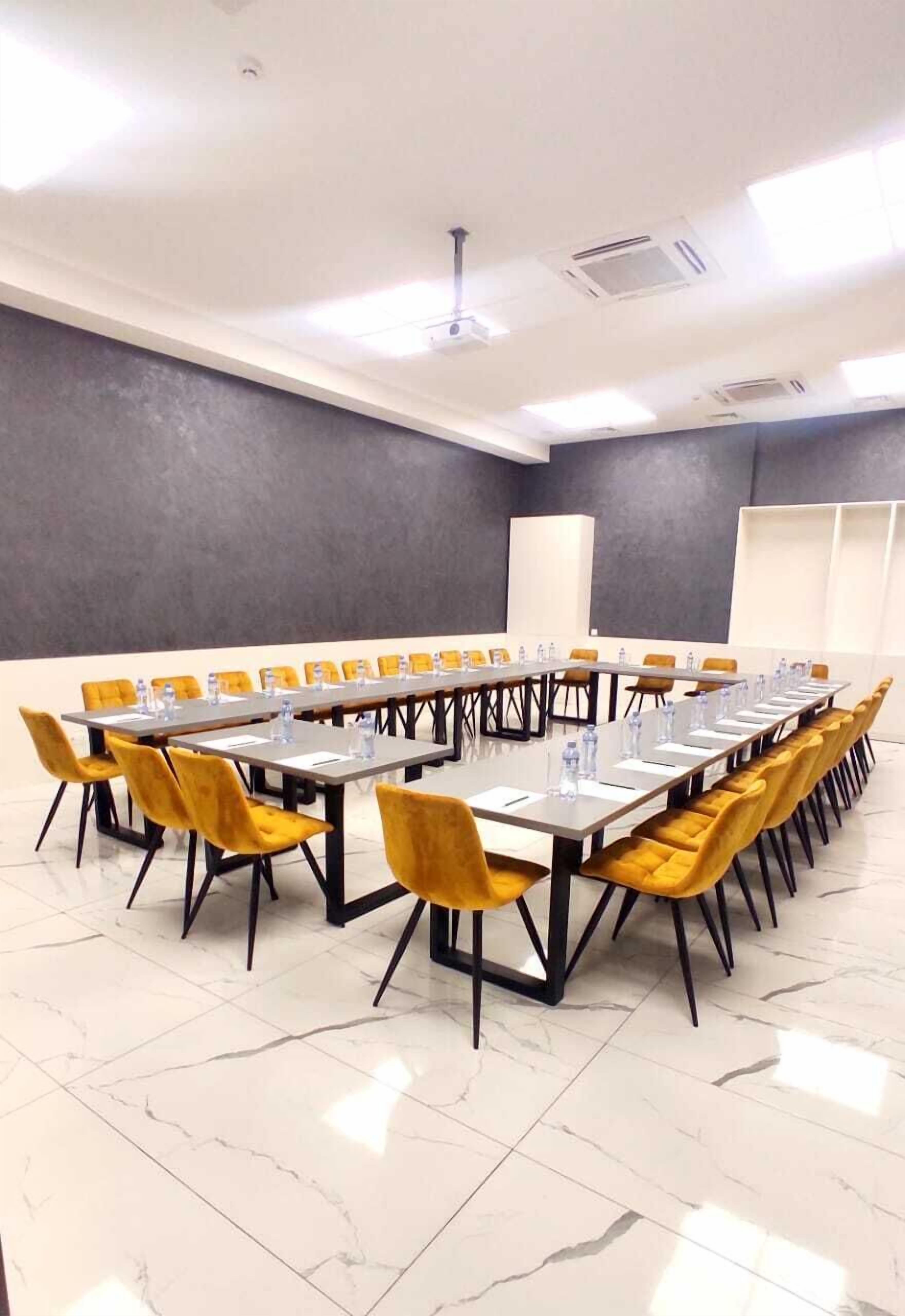 Una sala de conferencias con una larga mesa, sillas amarillas y techo blanco.