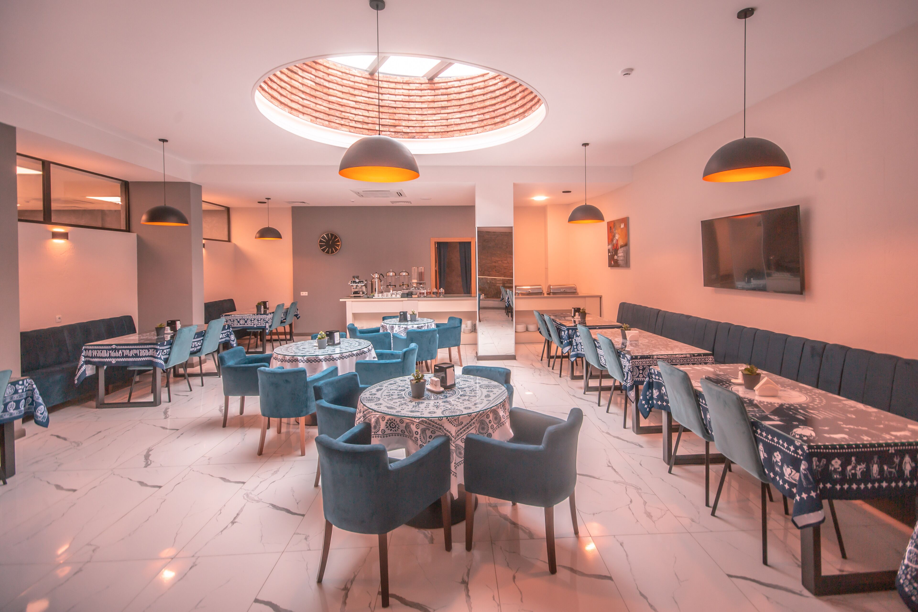 Un restaurante con mesas redondas, sillas azules y una zona de bar central.