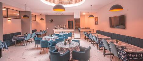Un restaurante con mesas redondas, sillas azules y una zona de bar central.