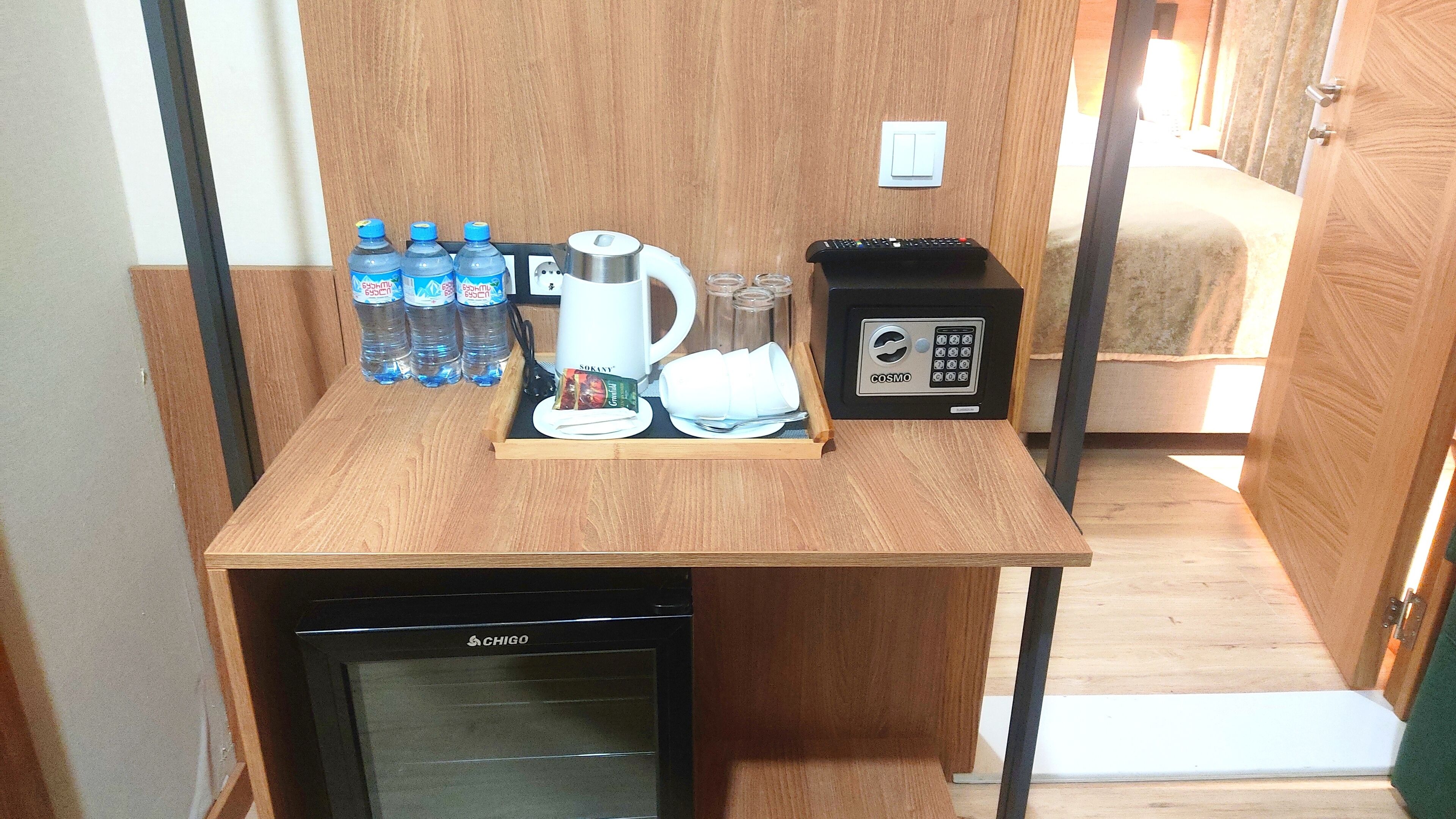 A kitchenette with a coffee maker, water bottles, a toaster, and a small refrigerator.