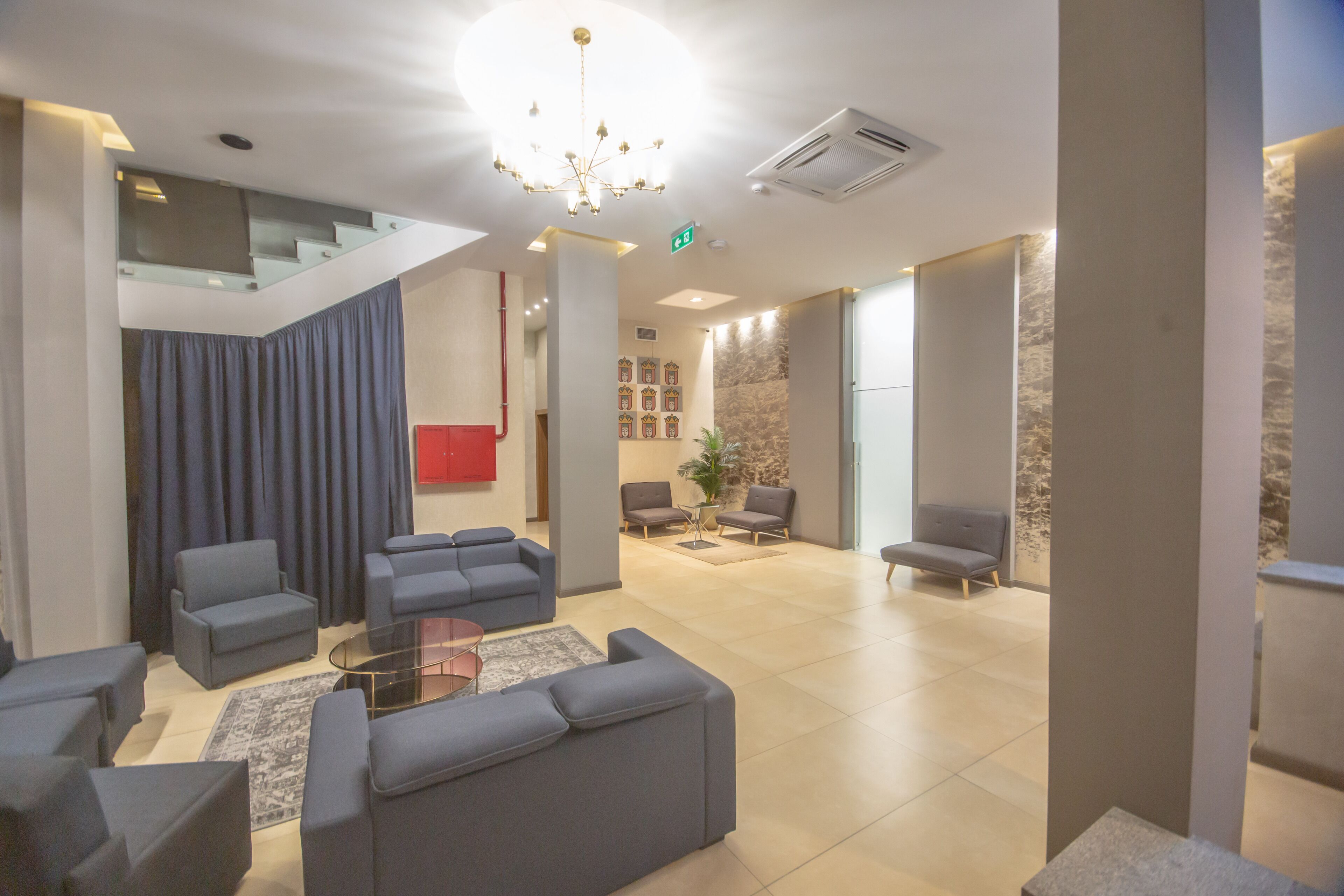 Un vestíbulo moderno con una escalera, zona de estar y mostrador de recepción.