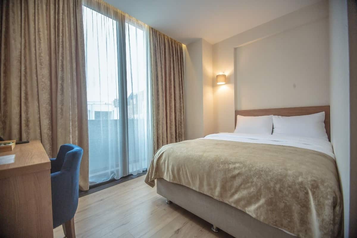 A hotel room with a bed, a desk, and a chair.