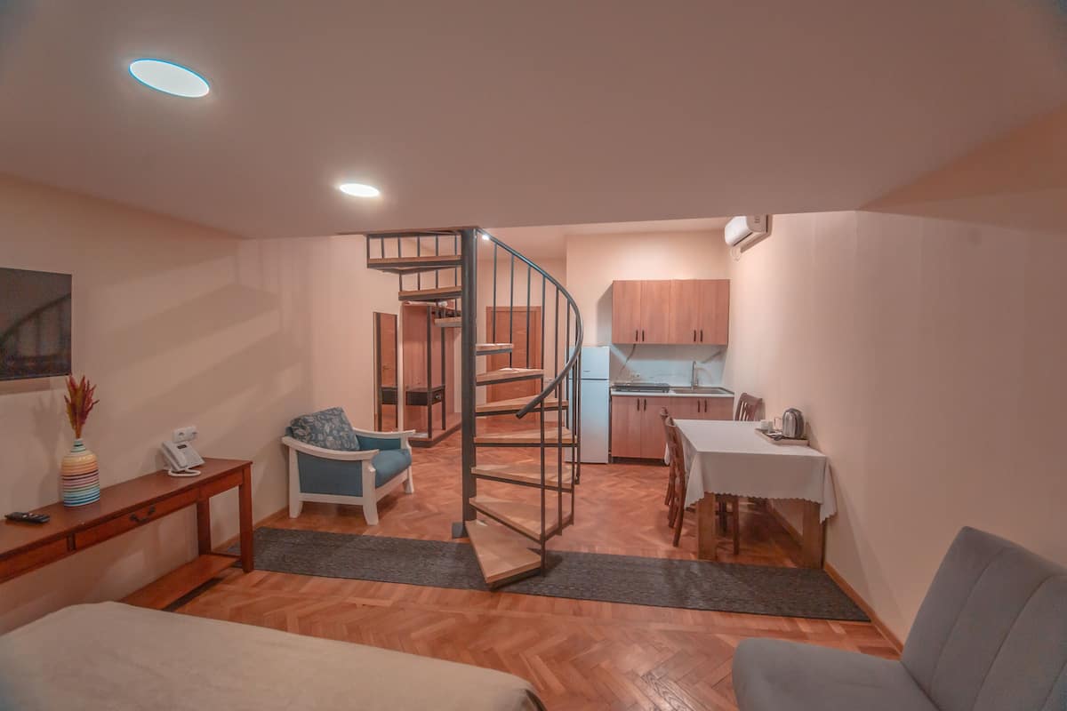 A compact living space with a kitchen, dining area, and a staircase leading to an upper level.