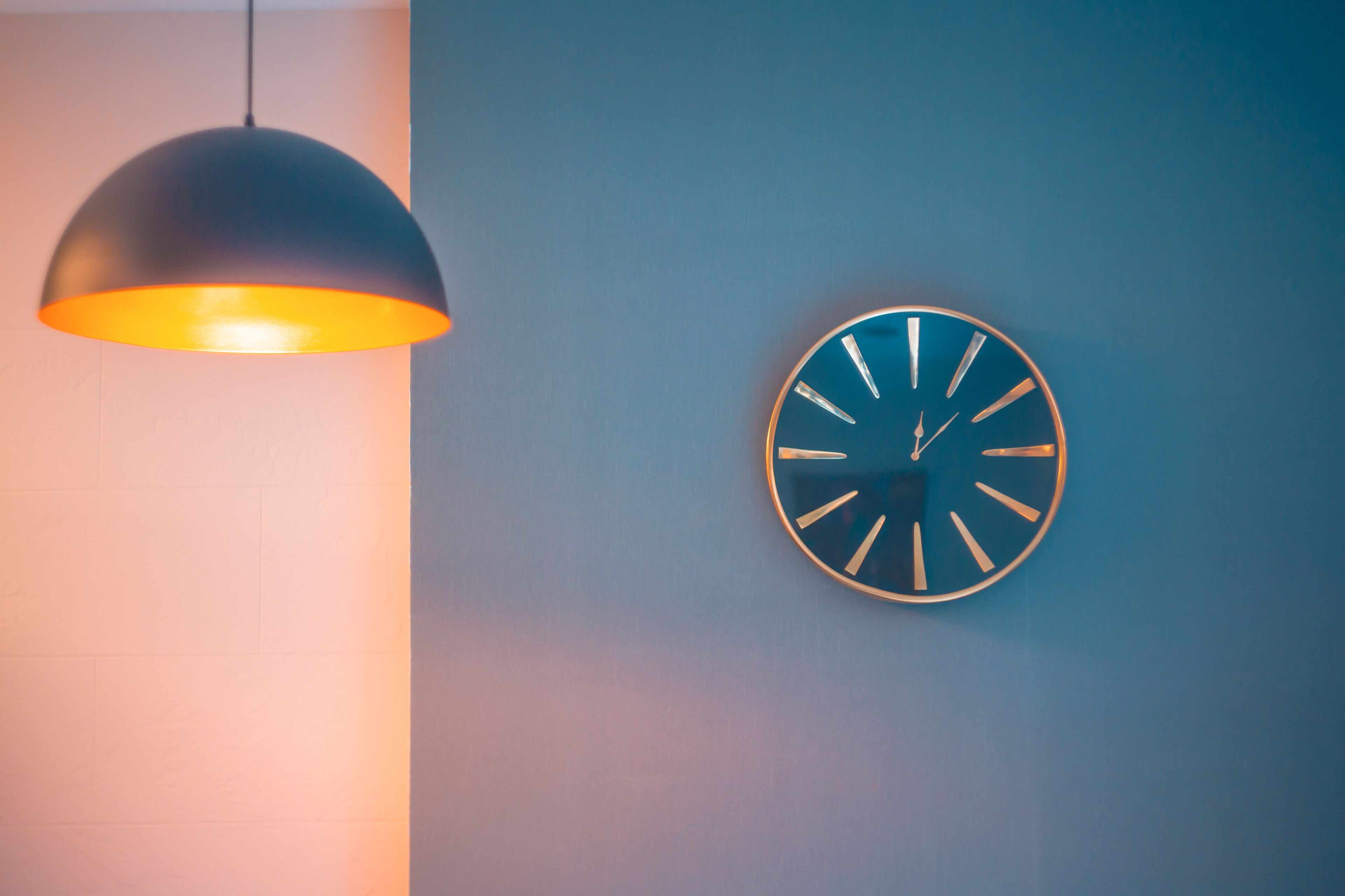 A wall-mounted clock with a circular face and hour markers, and a pendant light fixture with a dome-shaped shade.