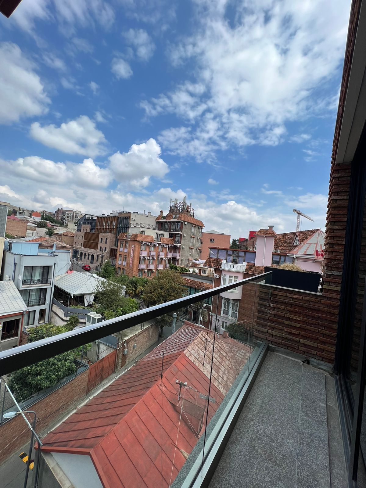 A balcony with a view of a cityscape, featuring various buildings and a clear sky.