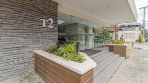 A modern building entrance with a stone facade, numbered 'T2', and a glass door.