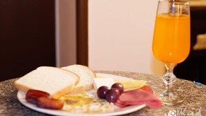 Un plato de desayuno con tostadas, huevos, jamón y queso, acompañado de un vaso de jugo de naranja sobre una encimera de granito.