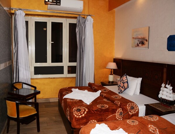 A hotel room with two beds, a chair, a table, and a window with curtains. - Cairo Dream Boutique Hotel (Cairo)