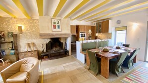 Una sala de estar acogedora con chimenea, un comedor con mesa y sillas de madera, y una cocina con armarios de madera y un ventanal.