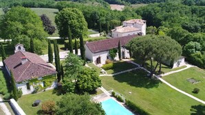Una extensa propiedad con piscina, varias edificaciones y abundante vegetación.