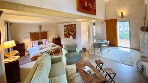 Amplia sala de estar con una cama grande, un sofá, una mesa de comedor y una chimenea.