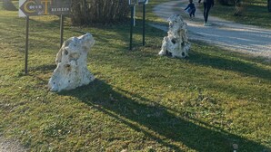 Un camino rural que lleva a una edificación de piedra con una pequeña torre, rodeada de árboles y un cartel que indica 'Cœur de Reilles'.