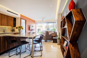 A modern kitchen with a bar area, seating, and a large window.