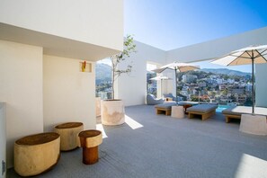 Terraza en la azotea con mobiliario, sombrillas y vistas a la ciudad.