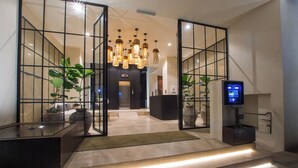 Un moderno vestíbulo de hotel con una recepción, un televisor y una escalera que sube a los pisos superiores.