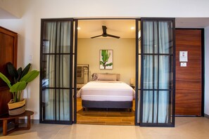 A bedroom with a bed, a ceiling fan, a plant, and a sliding glass door. - Modern 2BR Near Beach & Boardwalk | Gym & BBQ (Puerto Vallarta)